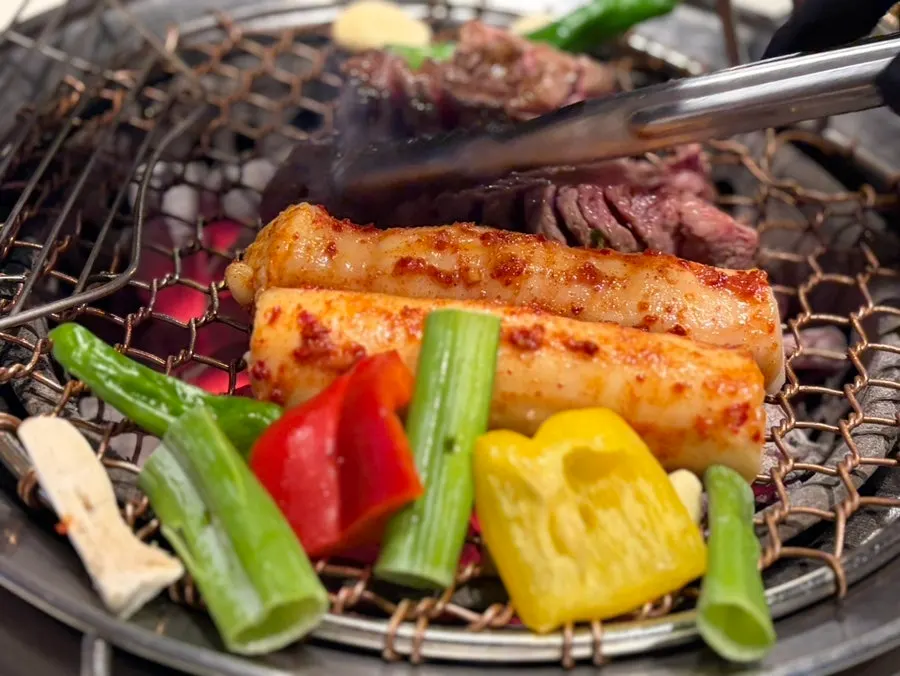 A staff member grilling meat over charcoal