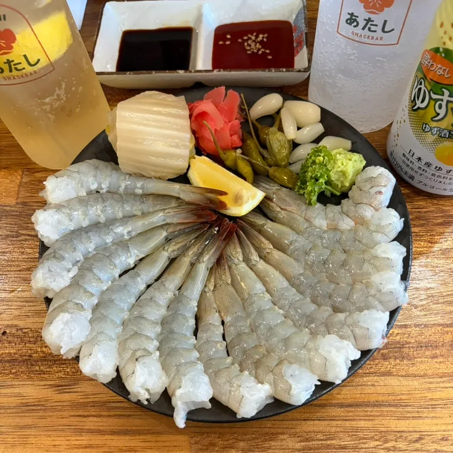 A plate of raw shrimp sashimi served with aged kimchi and pickled radish