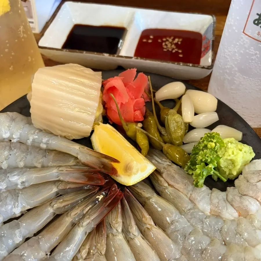 Close-up of a plate of 15 pieces of raw shrimp sashimi