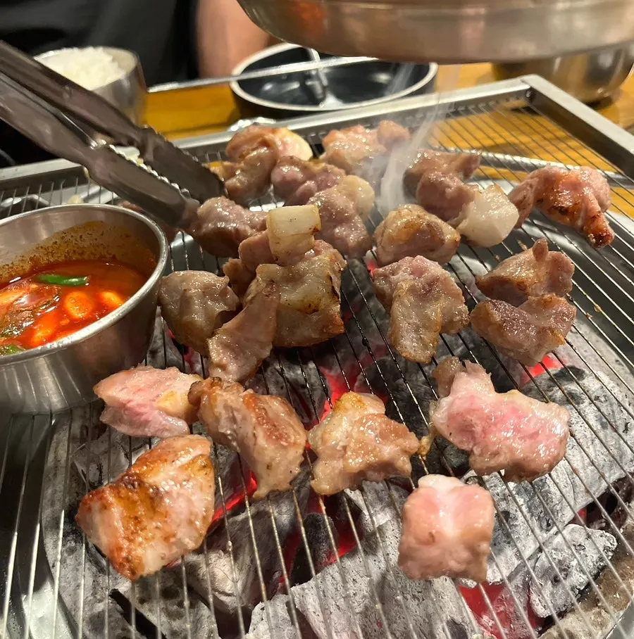 Kkodeulsal cooking alongside gulchi sokjeot on the grill