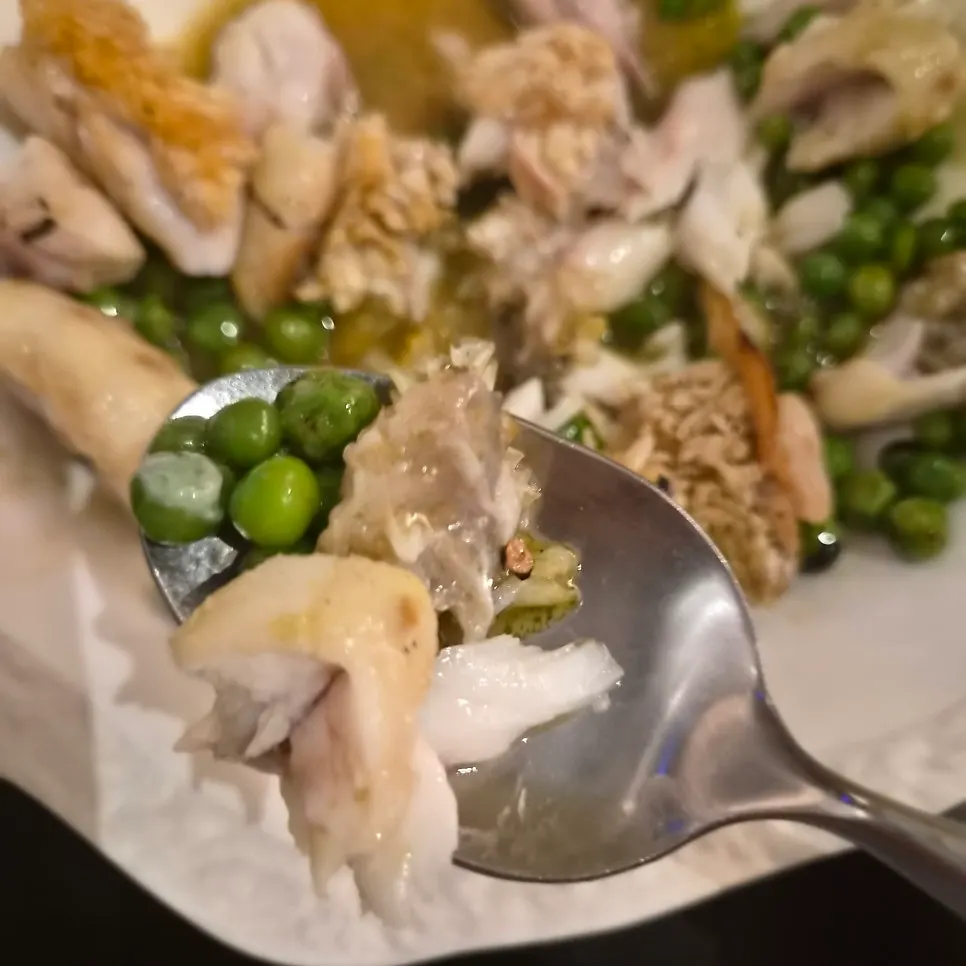Scooping tilefish flesh together with sauce and peas