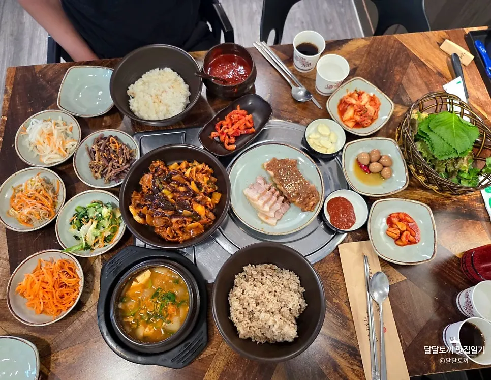 A full spread with black garlic jeyuk stir-fry, bossam, and doenjang jjigae