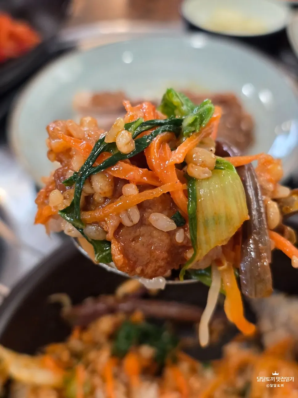 Barley bibimbap mixed with a final drizzle of sesame oil