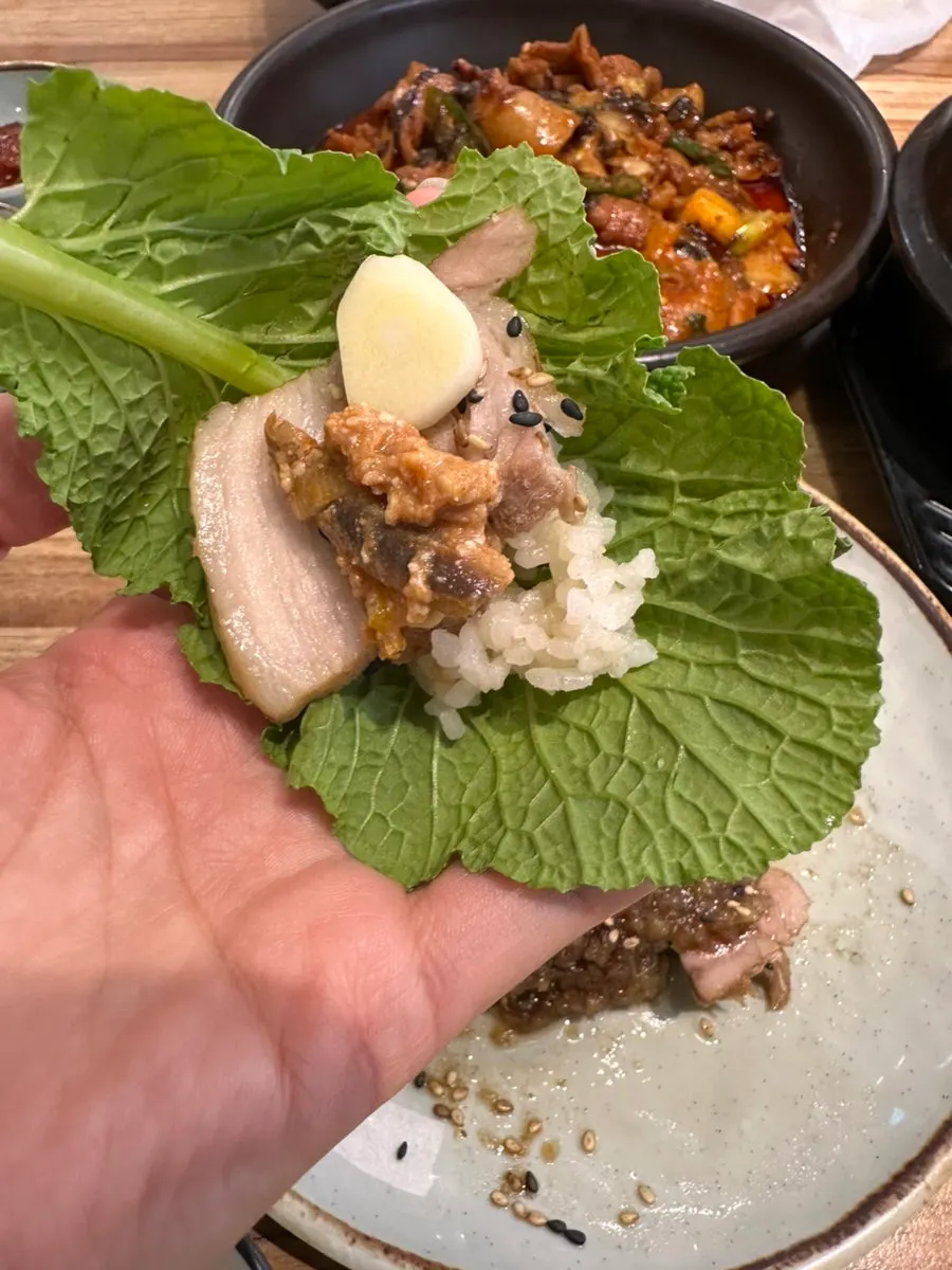 A piece of black garlic boiled pork dipped in sauce