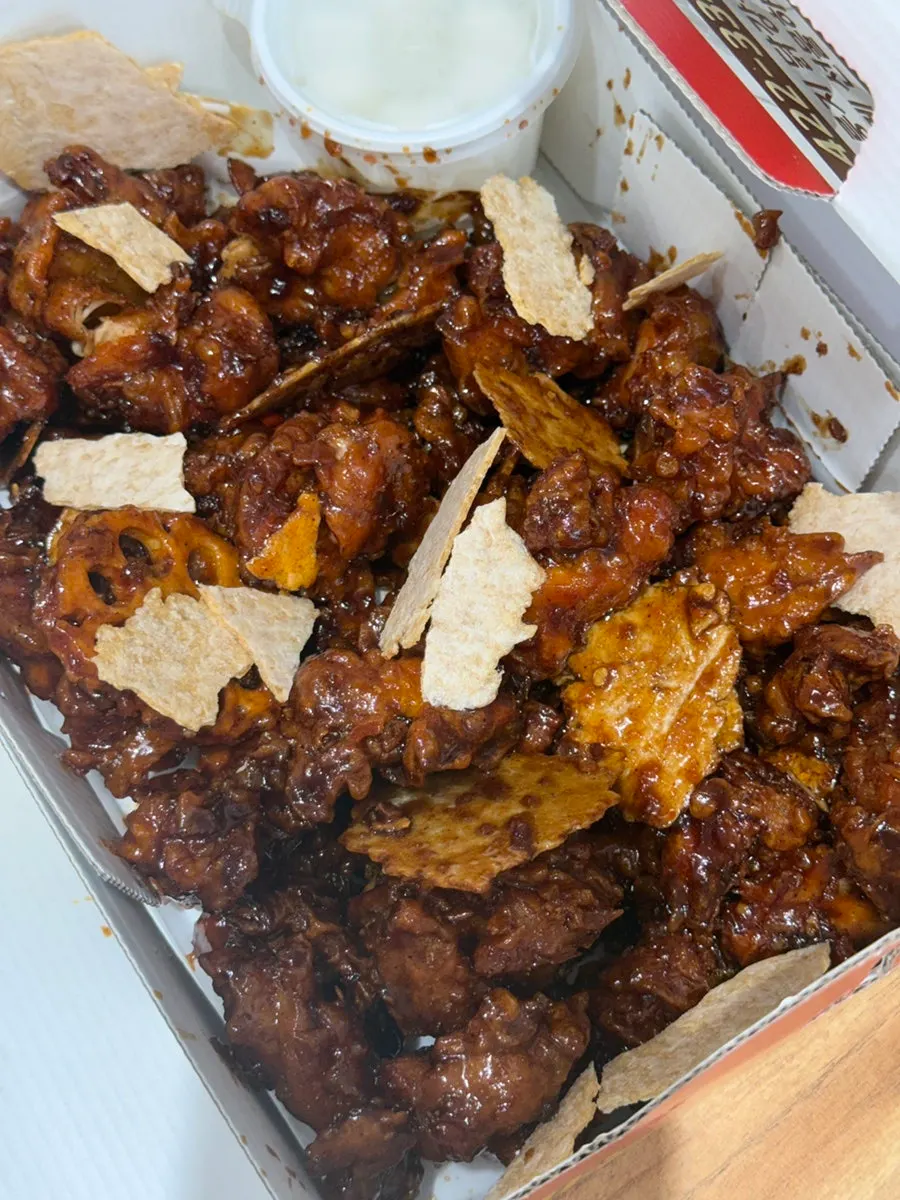 A sauce-coated piece of nurungji next to the dakgangjeong