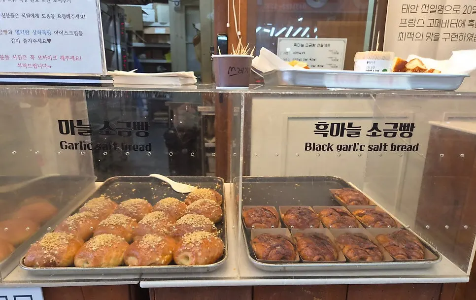 Display case with original, streusel, garlic, and black garlic salt bread