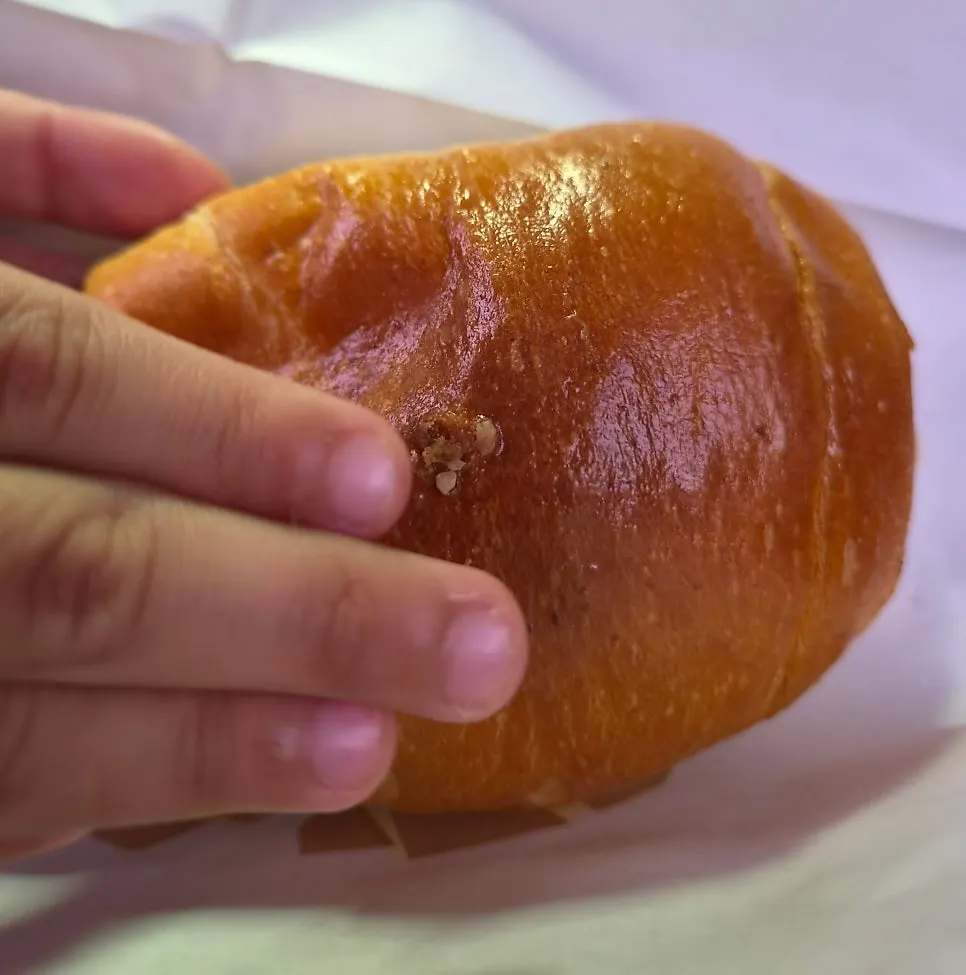 Original salt bread held in hand showing glossy crust