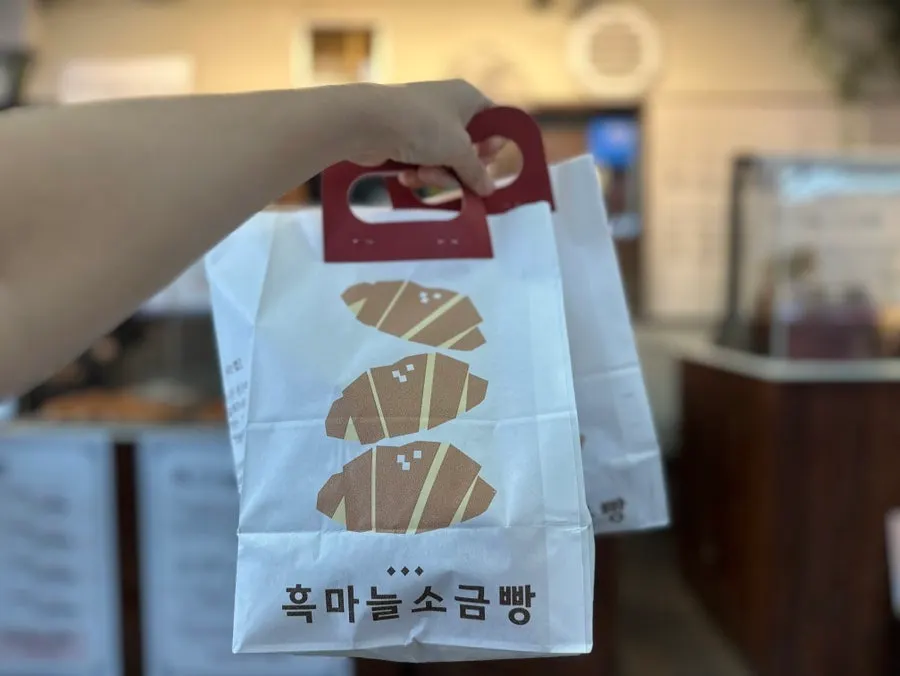 손잡이 달린 종이 포장지에 담긴 소금빵