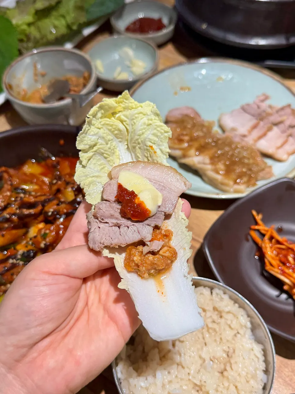 Wrap green topped with black garlic rice, boiled pork, and doenjang dip
