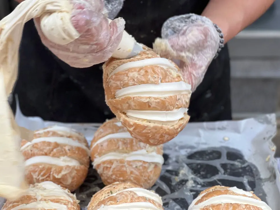 Baker filling garlic bread with cream cheese