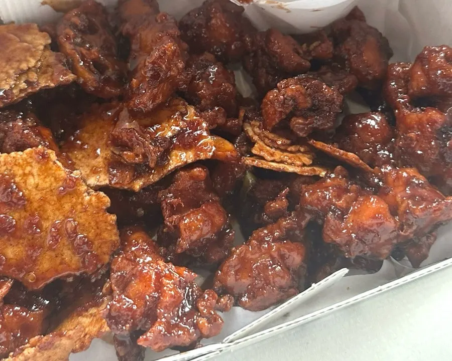 A box of black garlic fried chicken mixed with rice crust
