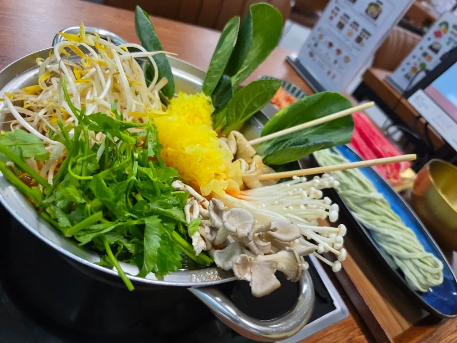 Shabu-shabu table setting piled with vegetables and mushrooms