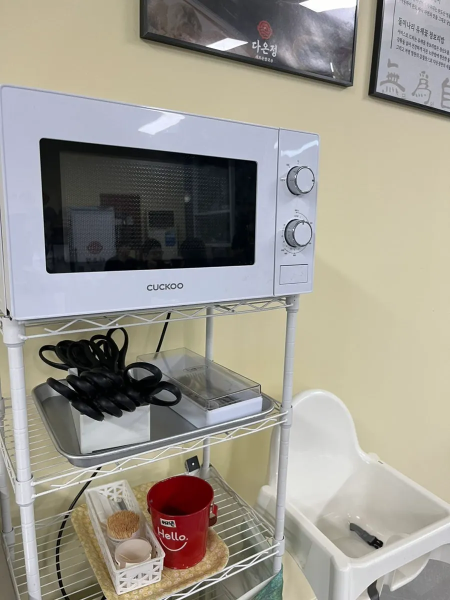 A corner of the restaurant with a baby chair and microwave