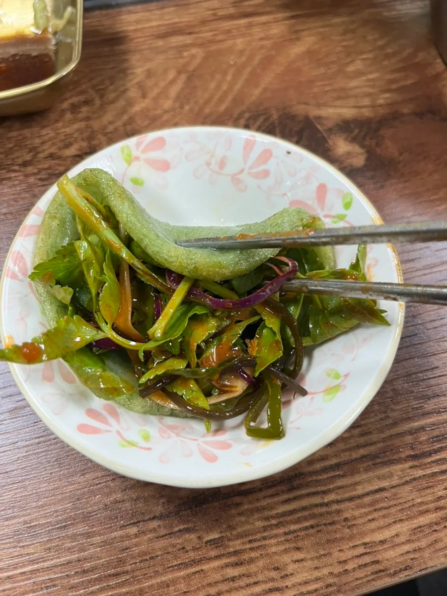 A piece of maesaengi pancake topped with the mixed seaweed