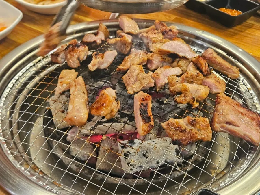 집게로 고기를 불판 가장자리로 옮기는 모습