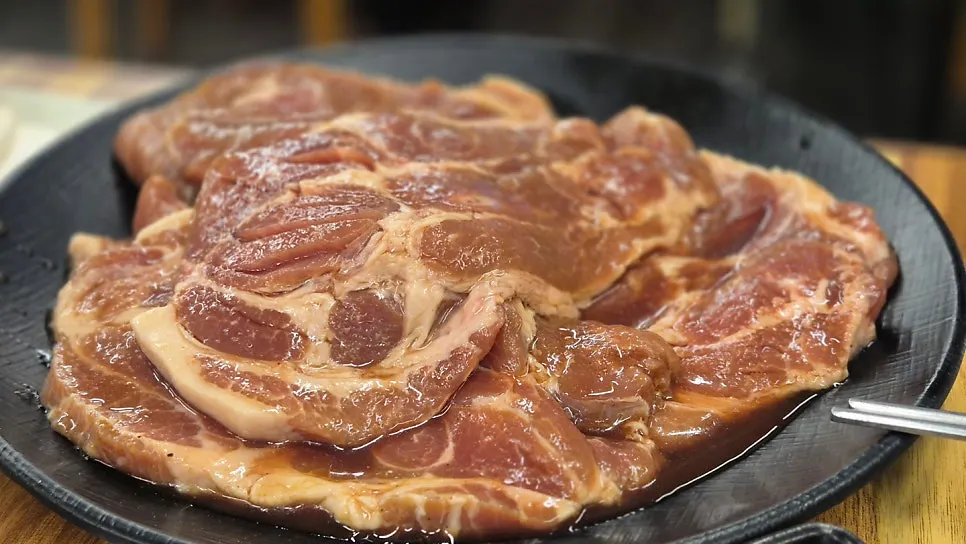 Vivid reddish-pink domestic raw pork placed on the charcoal grill
