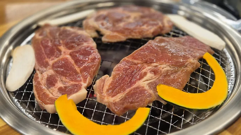 Marinated pork neck cooking over charcoal