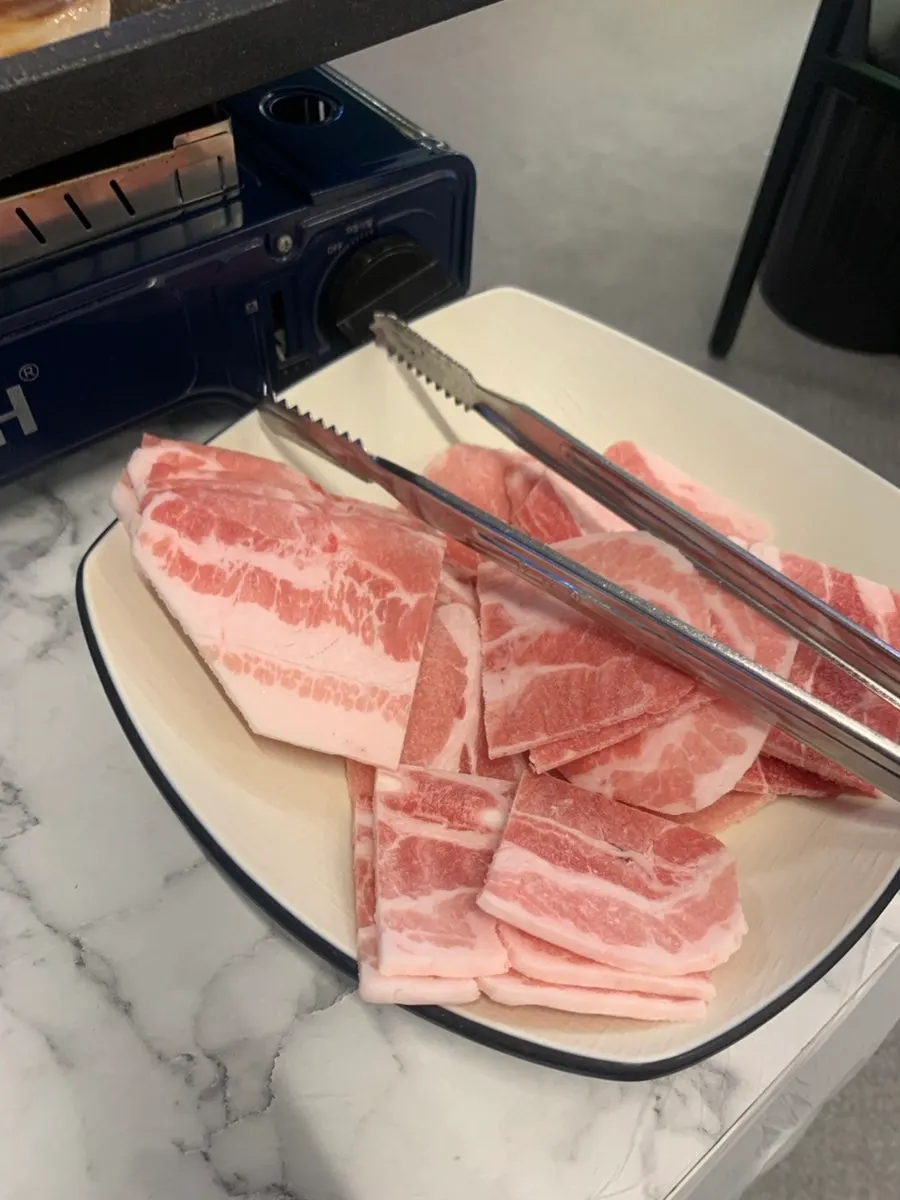 파채와 쌈 야채를 곁들인 삼겹살 한 점