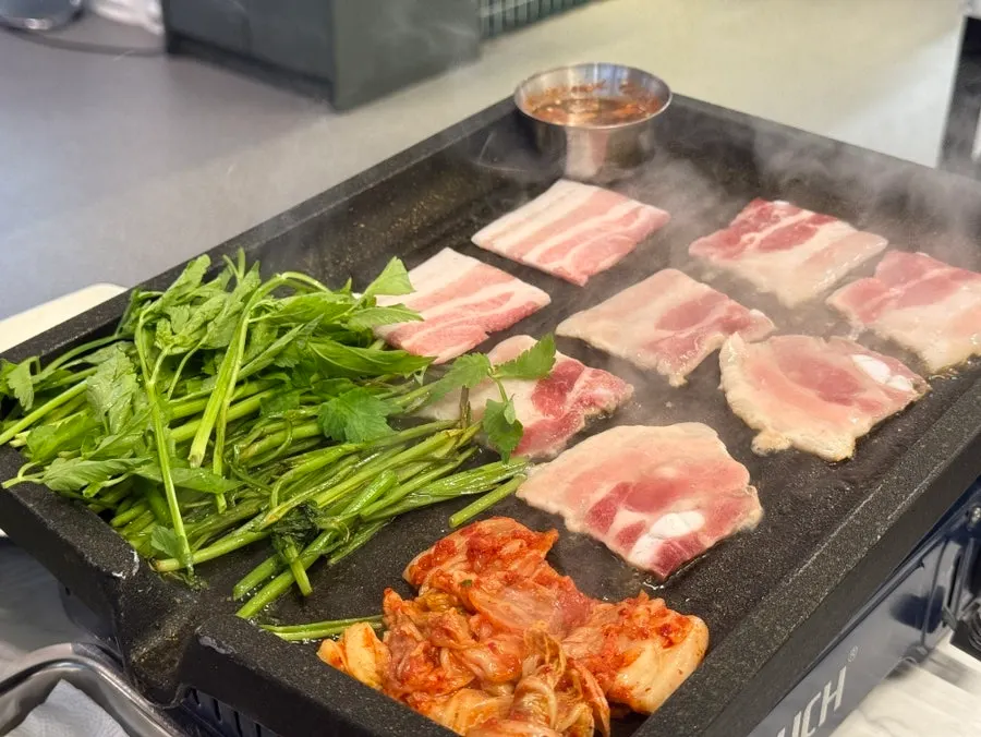 Minari grilled alongside the pork belly