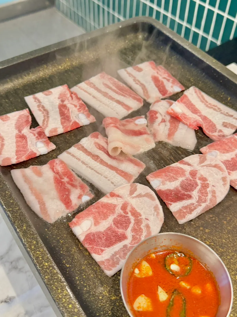 Flash-frozen samgyeopsal placed on the heated stone plate