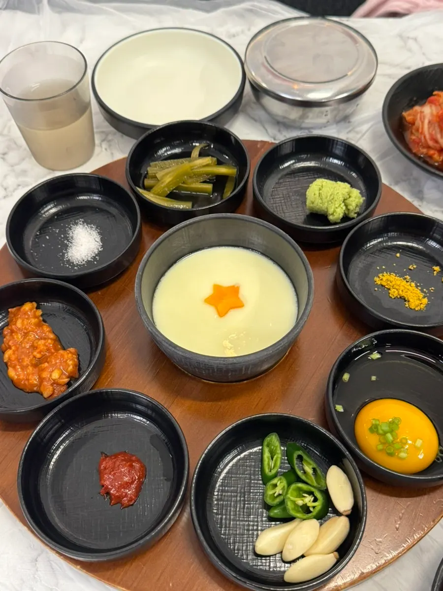 Assorted side dishes for pork belly including fresh wasabi and shredded scallions