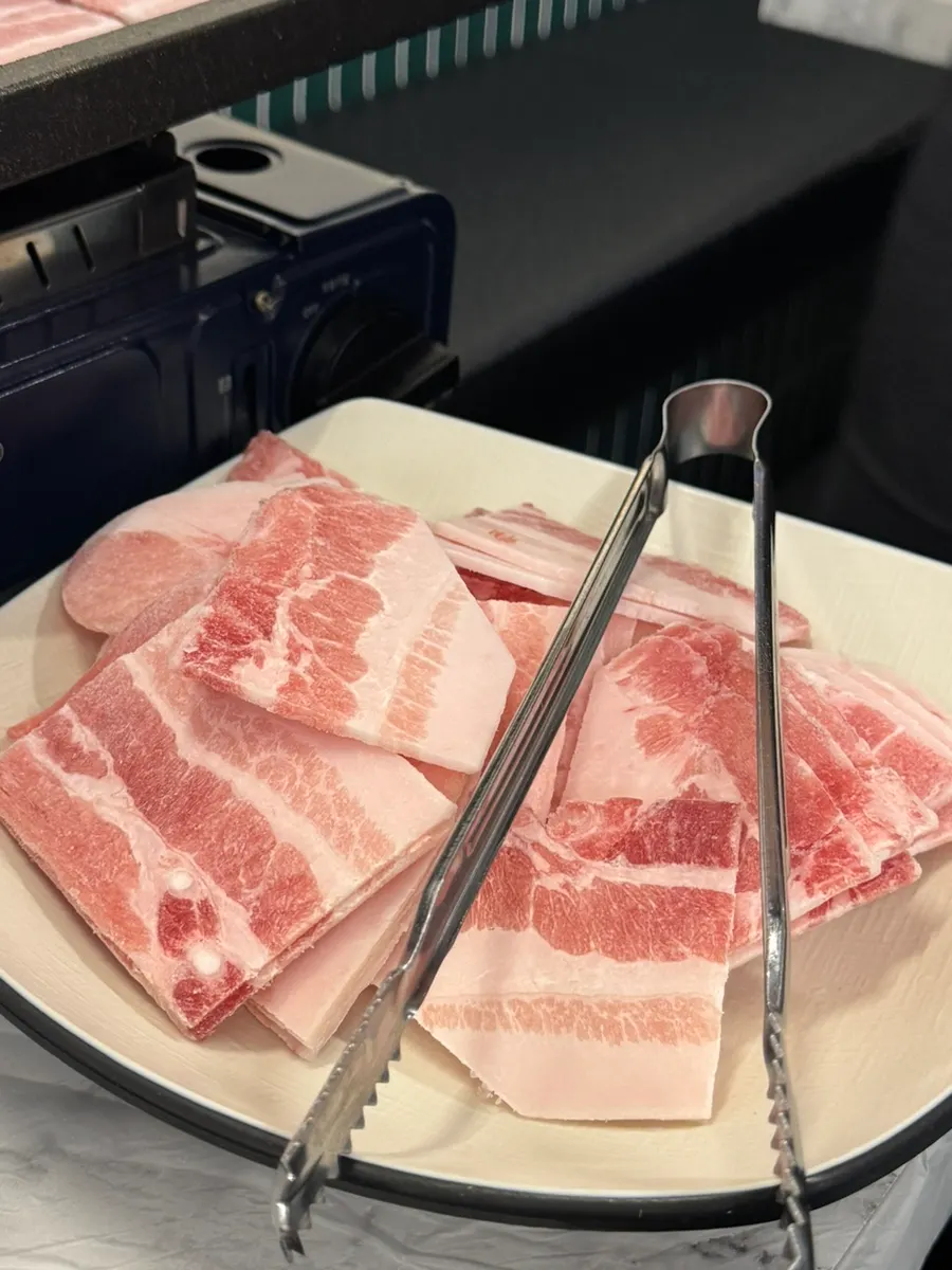 Thin frozen pork belly slices on the grill