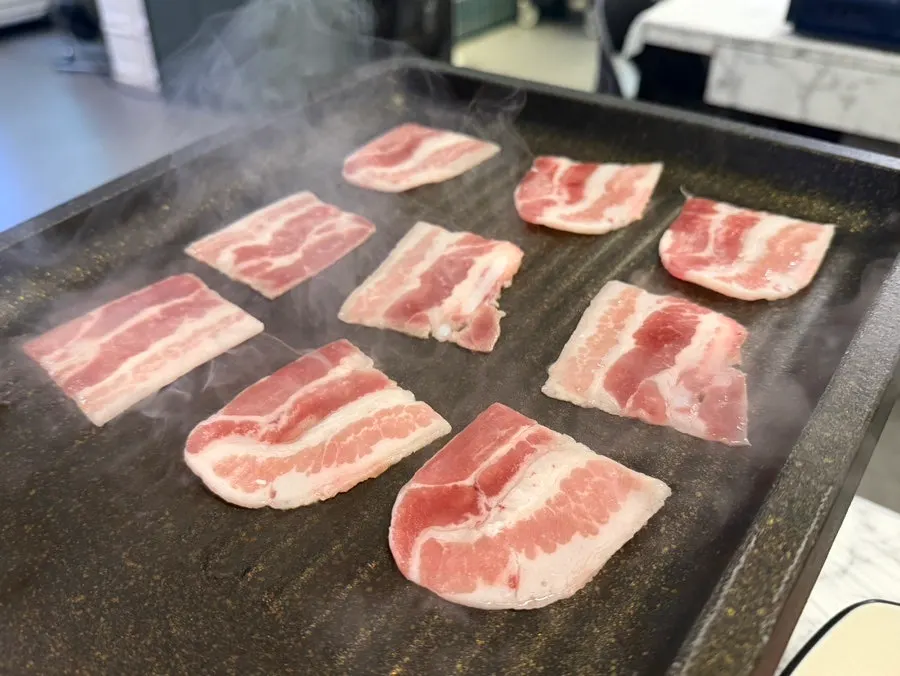Frozen pork belly turning golden-brown on the grill