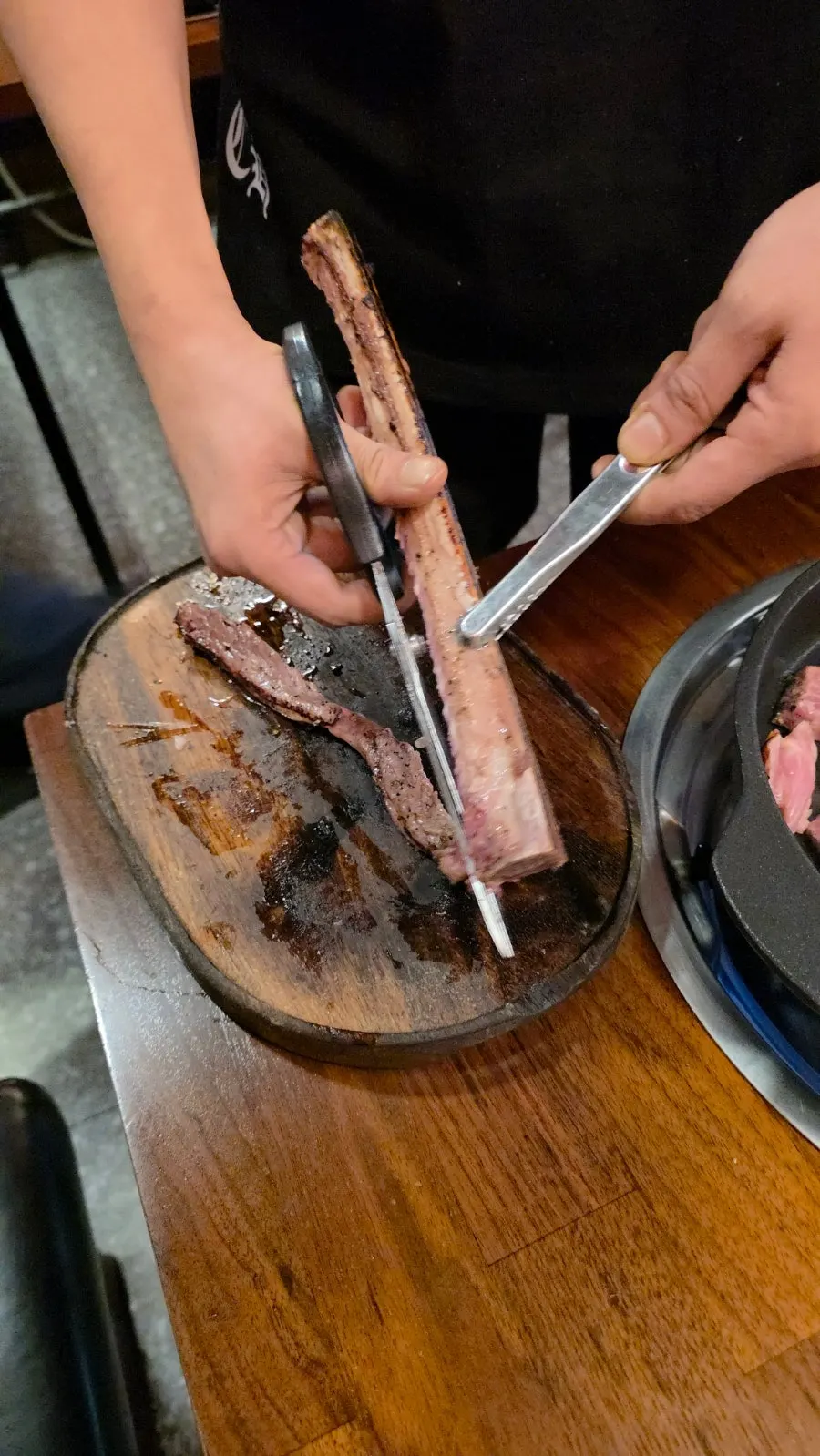 Staff member trimming and grilling meat off the bone