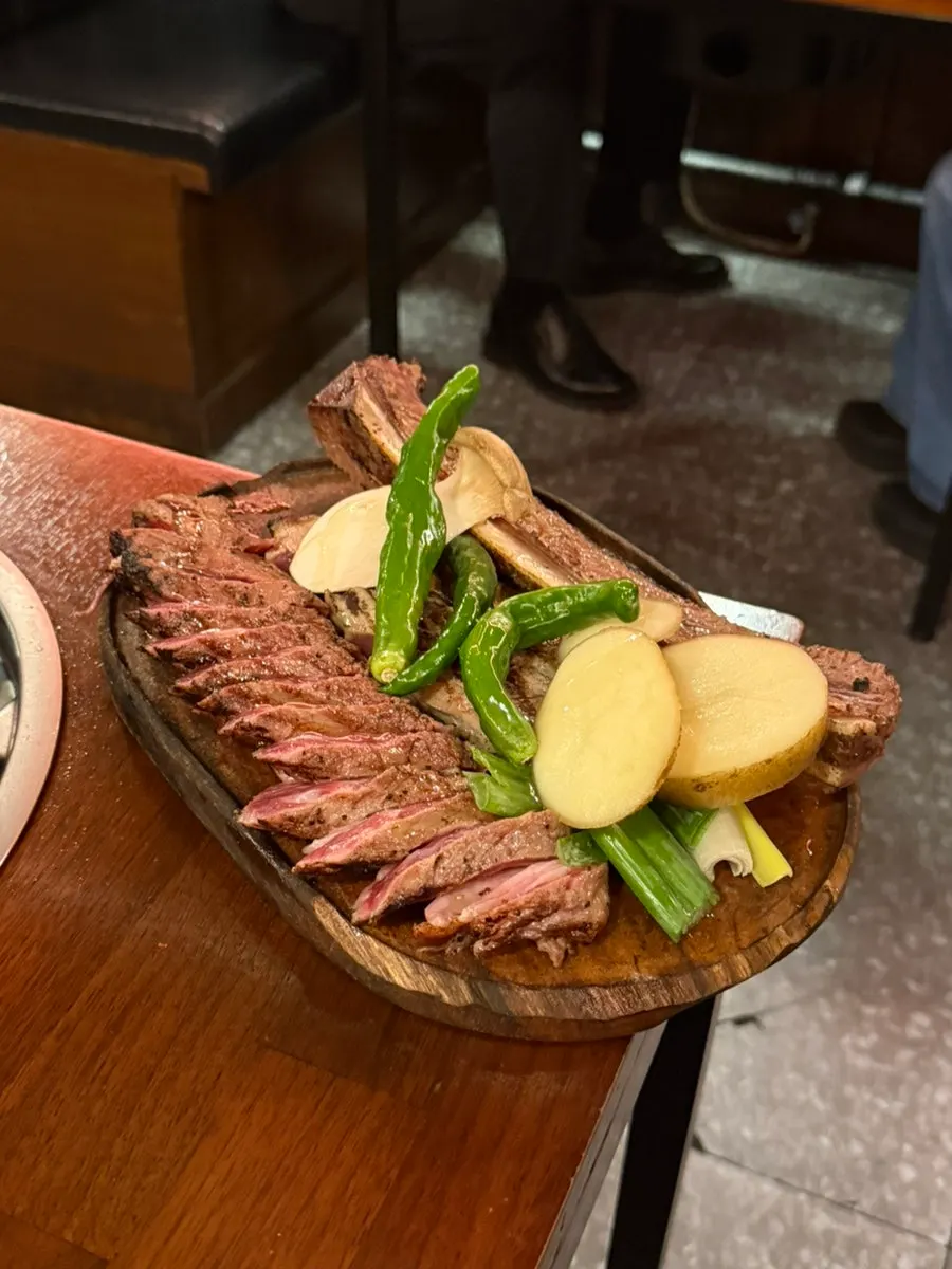 A plate of charcoal-seared aged woodae galbi with side dishes