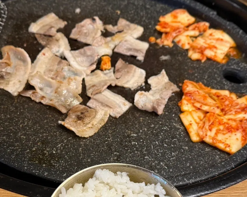 불판 위 대패삼겹살과 함께 구워지는 김치와 마늘