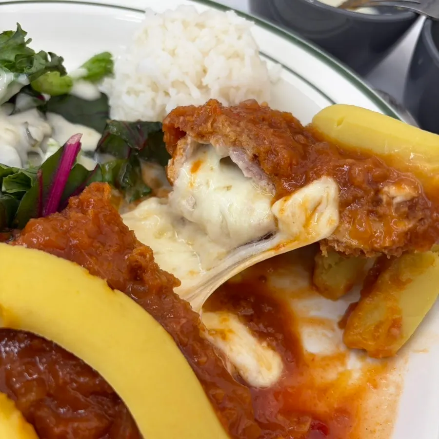 A piece of pork cutlet with cheese oozing out