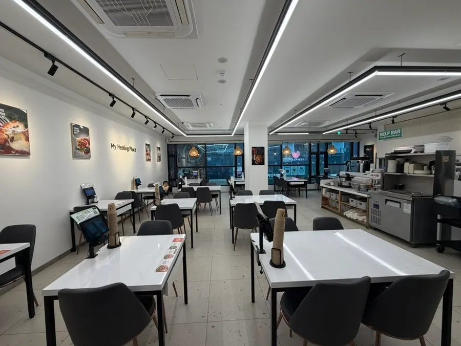 Interior luminoso en tonos blancos del salón de Tteudon Magok Branch