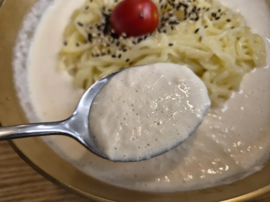 Lifting up a bite of kong-guksu noodles