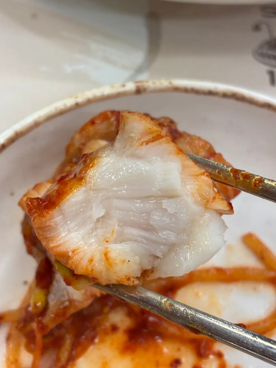 Chopsticks lifting a plump piece of monkfish