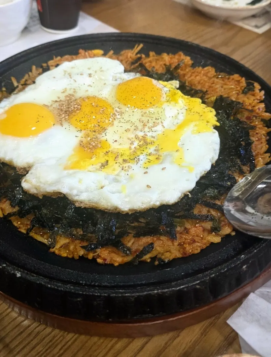 Three fried eggs served on top of the fried rice