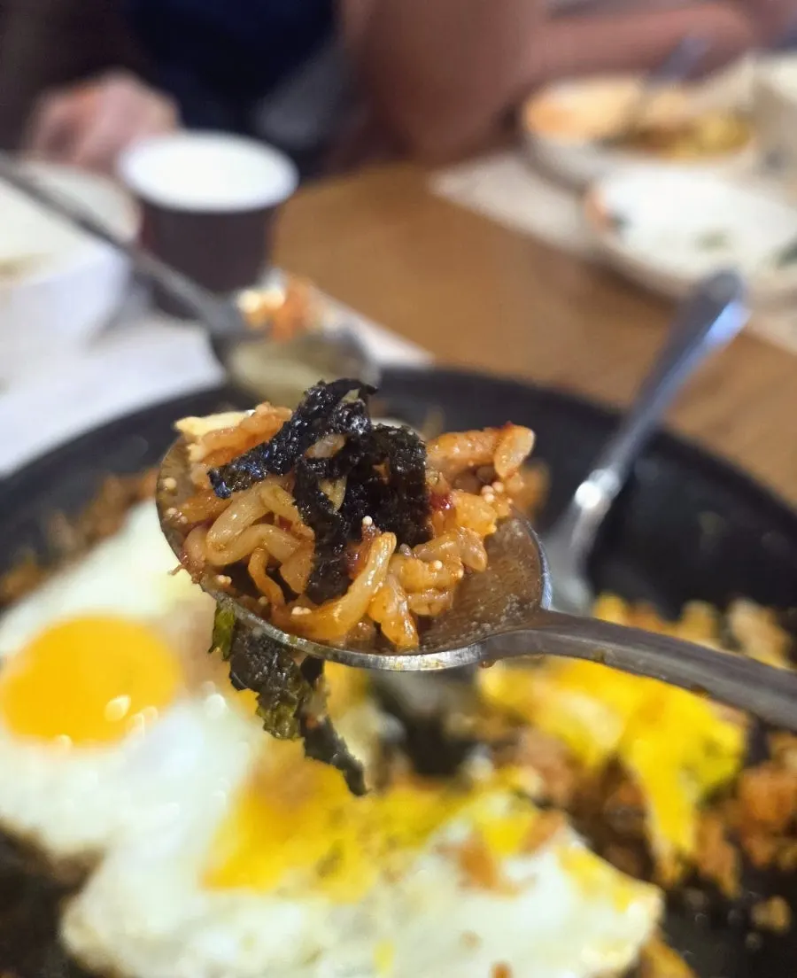 A spoonful of fried rice mixed with seaweed flakes and flying fish roe