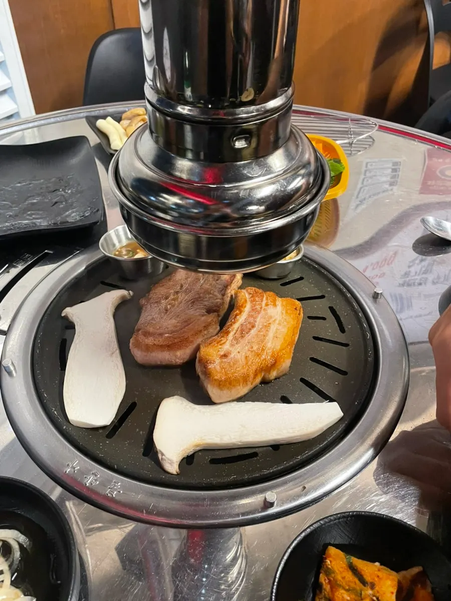 Thick pork belly being cut on the grill