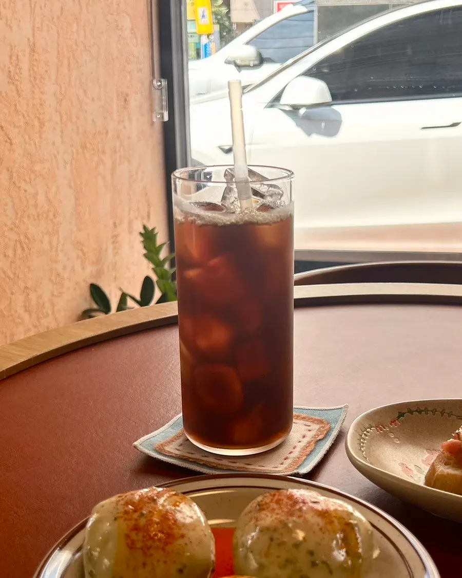 Iced drip coffee served with potatoes and open sandwiches