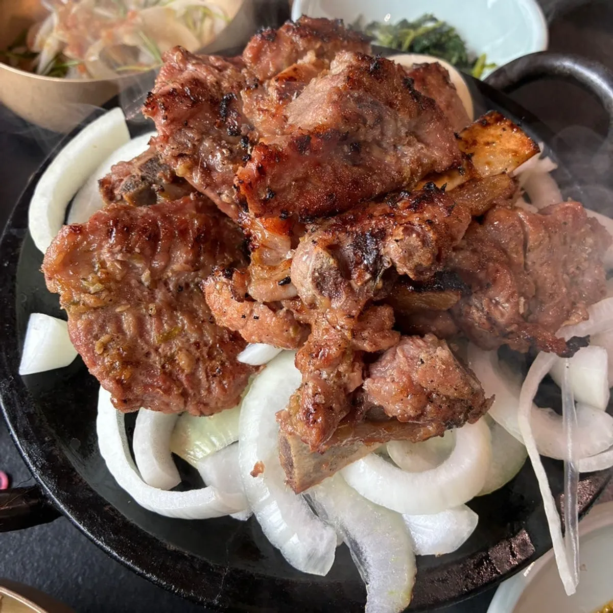 铺在铁盘洋葱上端出的炭火猪排骨