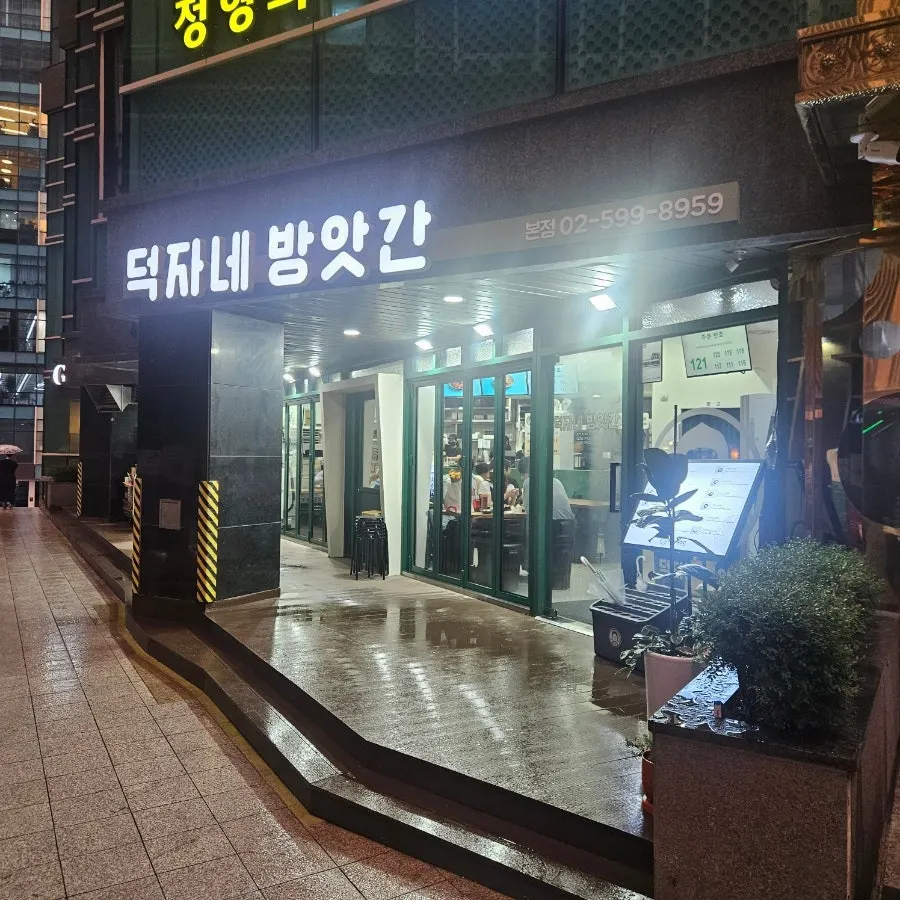 Deokjane Bangatgan's lit-up sign and entrance on a rainy evening