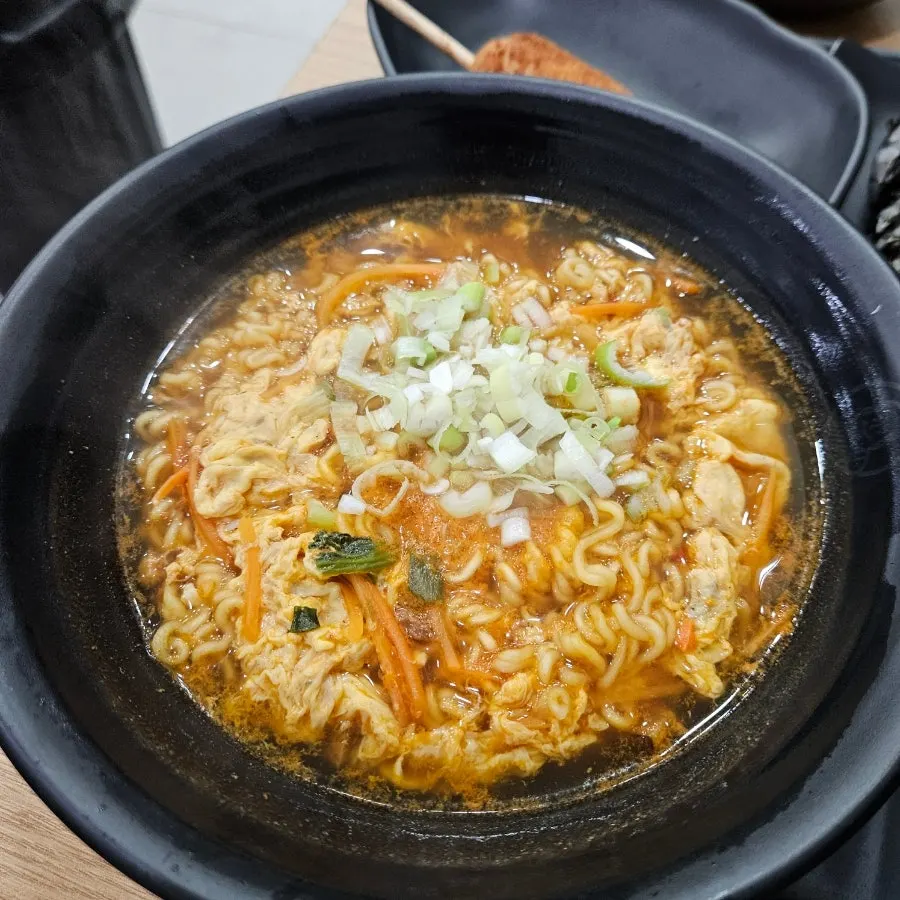 A bowl of spicy ramyeon topped with scallions and egg