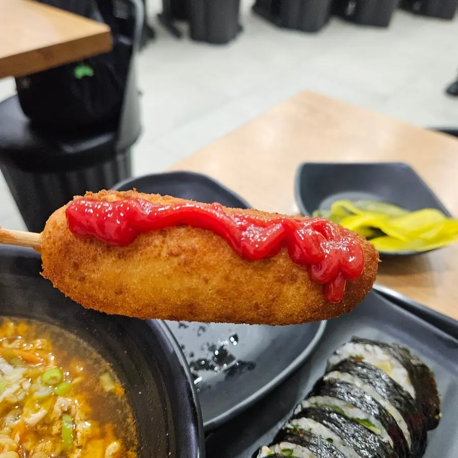 A ketchup-topped hot dog with pickled radish