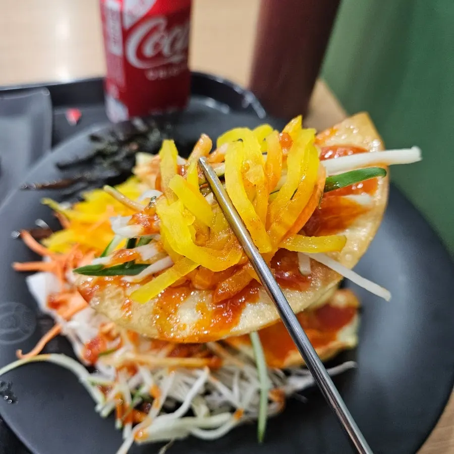 A bite of bibim mandu topped with pickled radish
