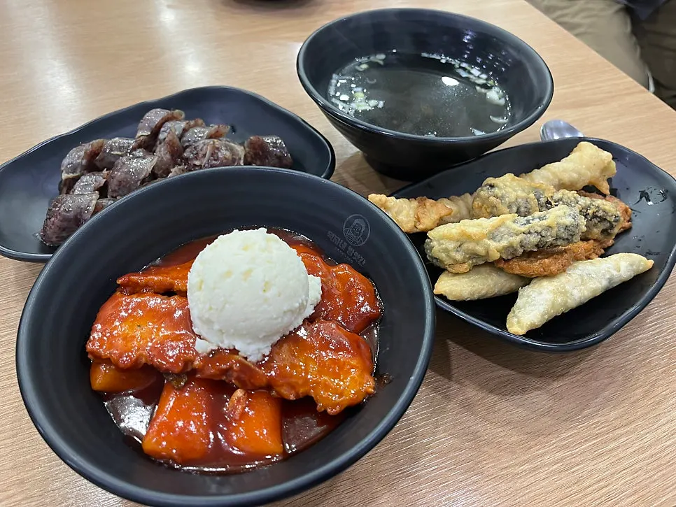 Table spread of tteokbokki, sundae and fried snacks at Deokjane Bangatgan