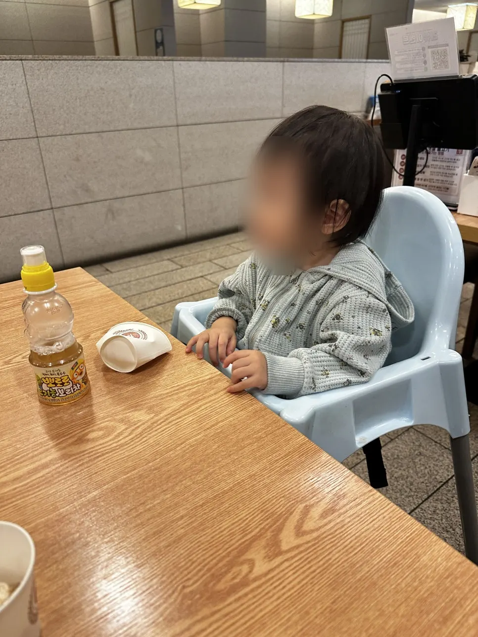 15-month-old baby eating while seated in a high chair