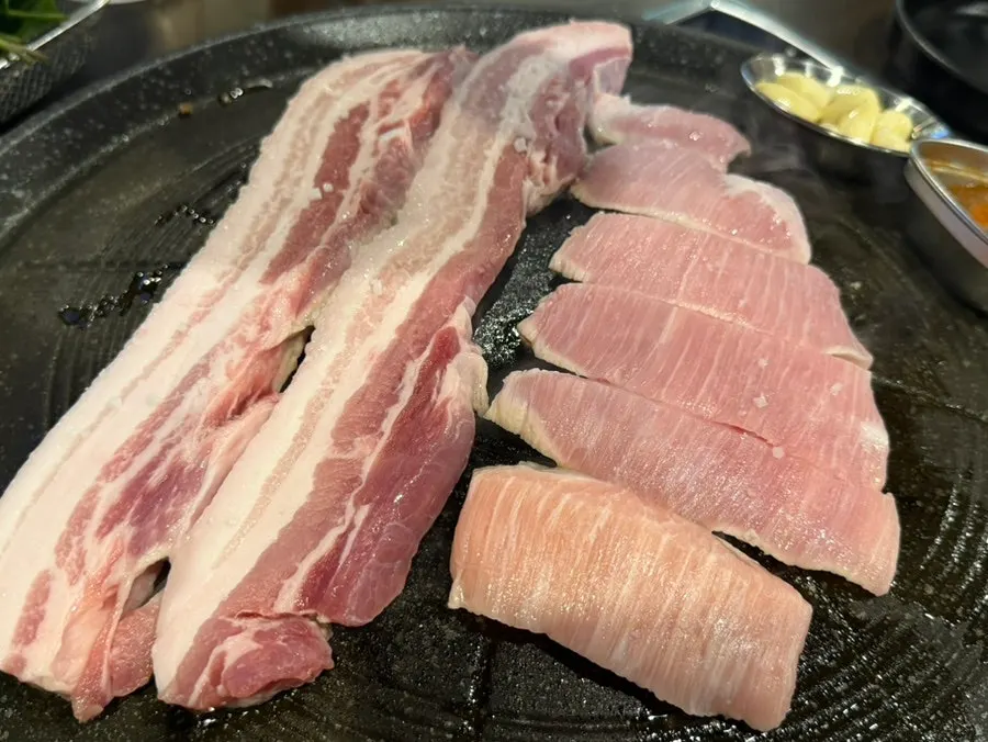 Pork belly and pork jowl placed on the cauldron lid