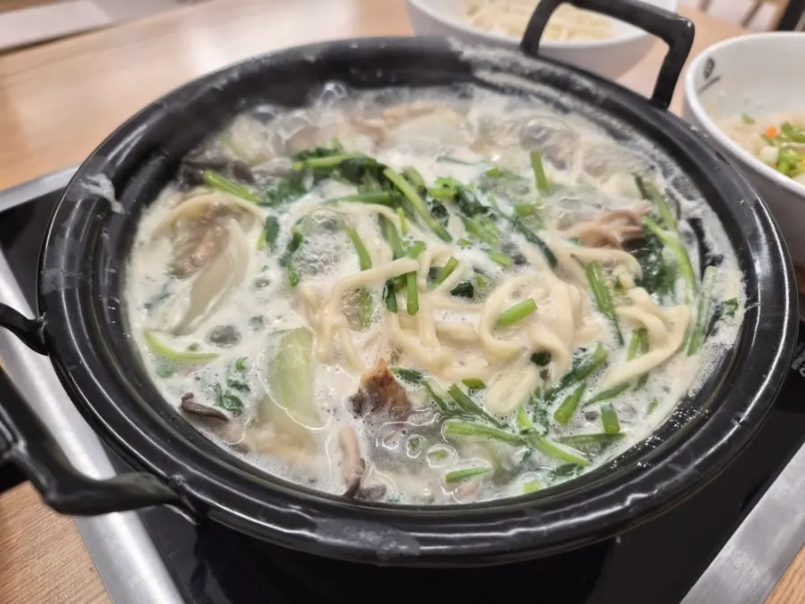 Clear mushroom kalguksu broth loaded with minari and mushrooms