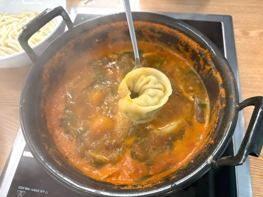 Adding kalguksu noodles and dumplings into the pot