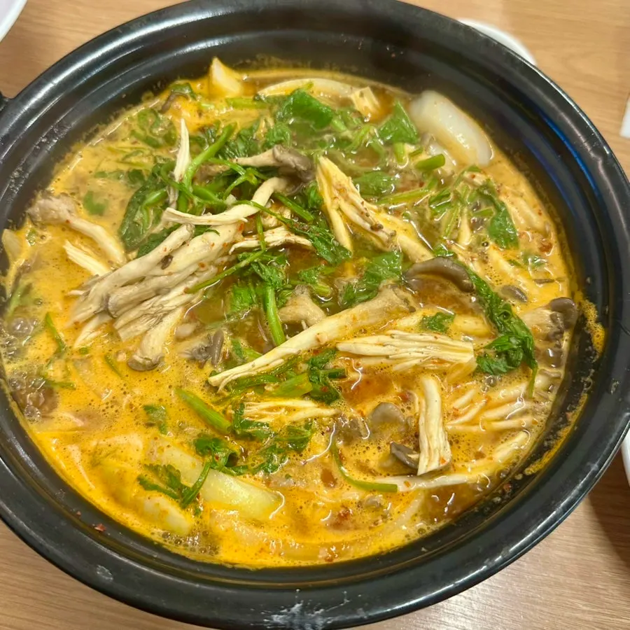 Spicy broth loaded with minari and mushrooms