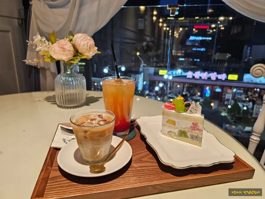 Cake and drinks set on the table by the window seat